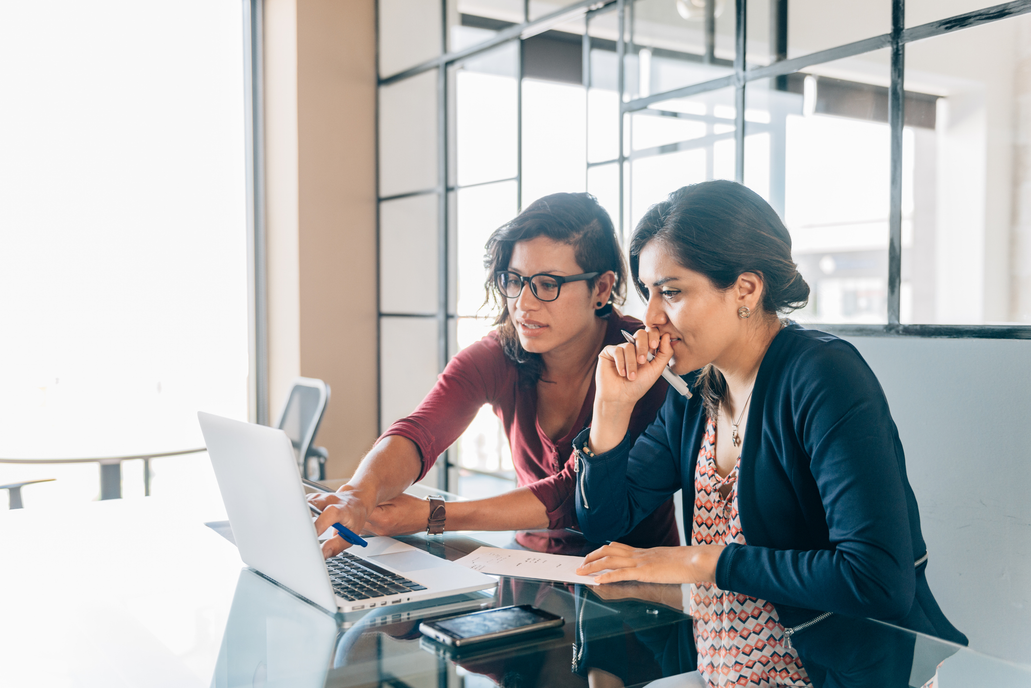Two women sitting and looking at a laptop.